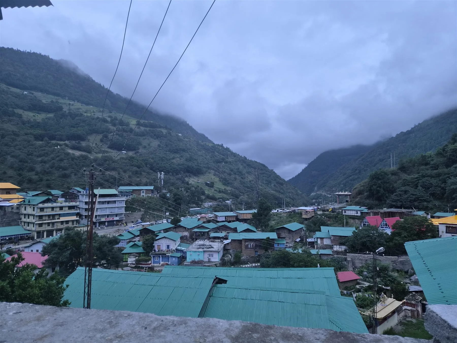 Dirang village roofs and mountain slopes beneath an evening sky