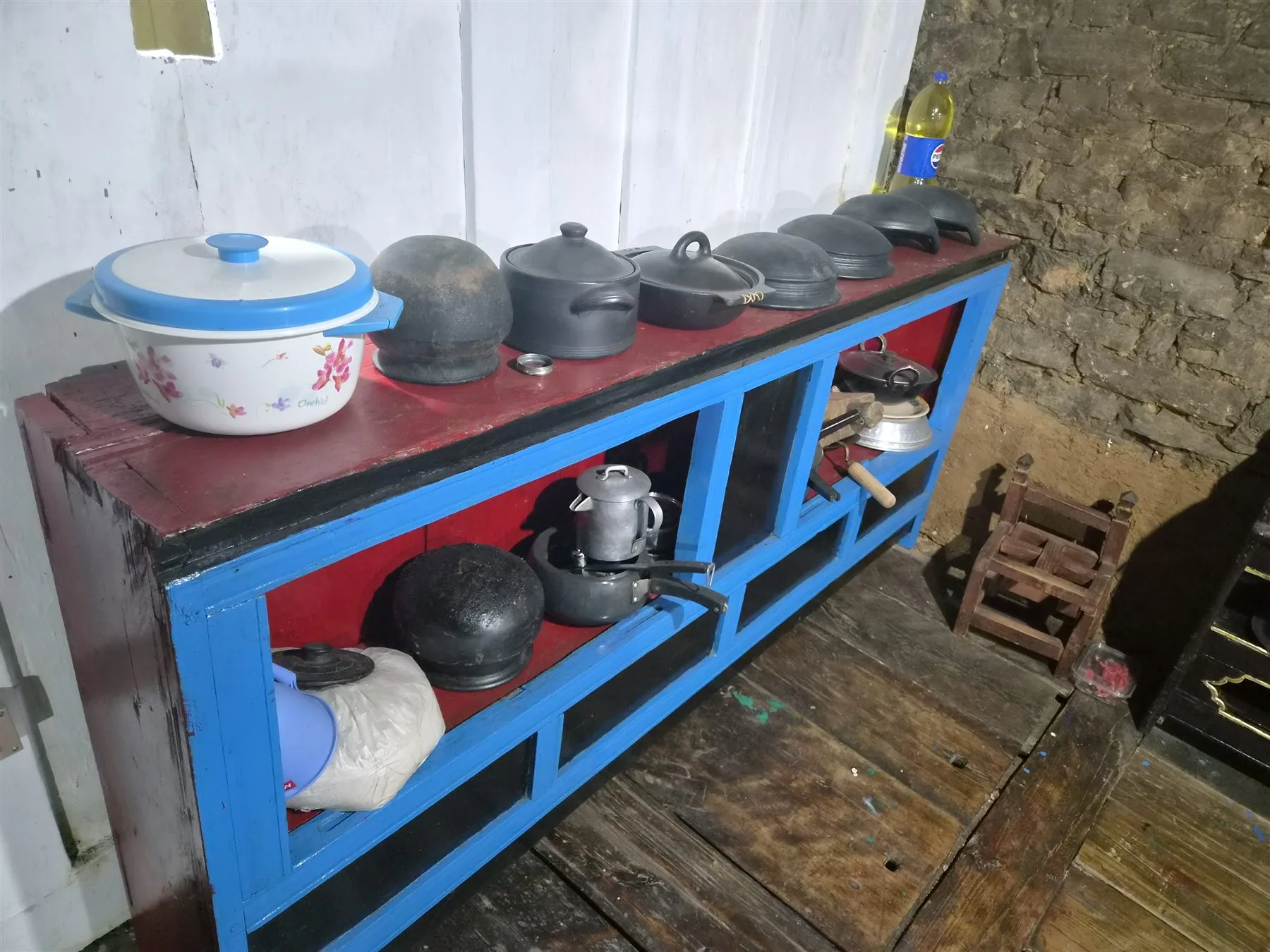 Traditional black cooking pots arranged on a blue wooden shelf